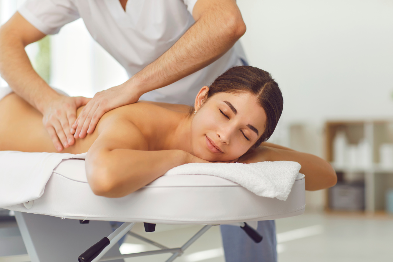 Relaxed Woman Enjoying Back Massage Done by Professional Masseur or Physiotherapist in Health Center